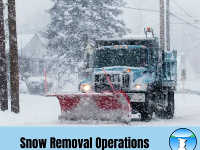 Blue snow plow driving on a snow covered road. 